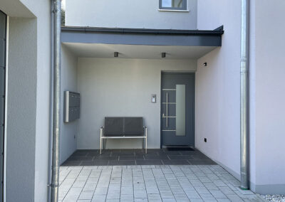 Überdachter Eingangsbereich von Mehrfamilienhaus in Massivbauweise